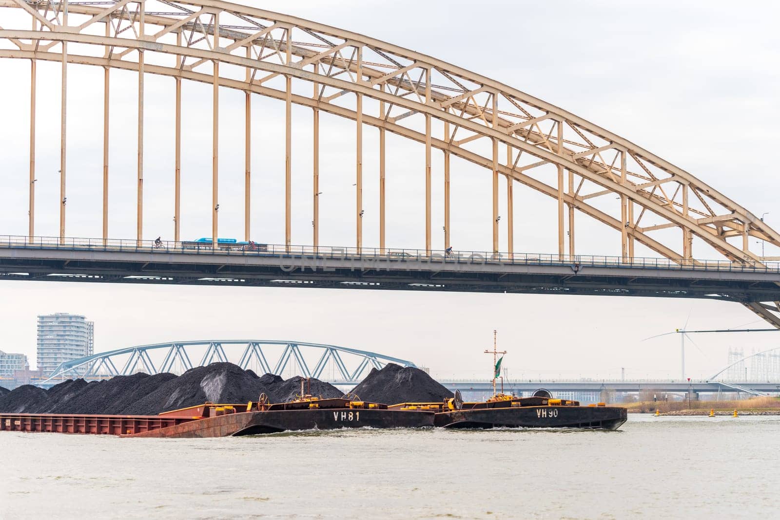 NIJMEGEN, NETHERLANDS - MARCH 9, 2024: Enormous dutch barge navigating the Waal river with a load of black sand