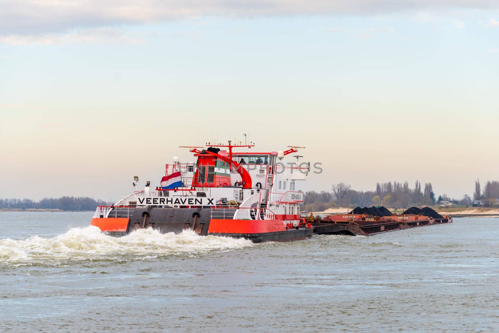 NIJMEGEN, NETHERLANDS - MARCH 9, 2024: Enormous dutch barge navigating the Waal river with a load of black sand