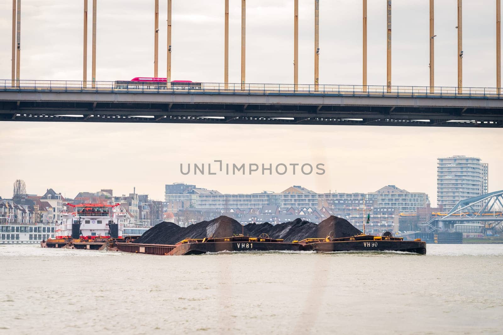 NIJMEGEN, NETHERLANDS - MARCH 9, 2024: Enormous dutch barge navigating the Waal river with a load of black sand