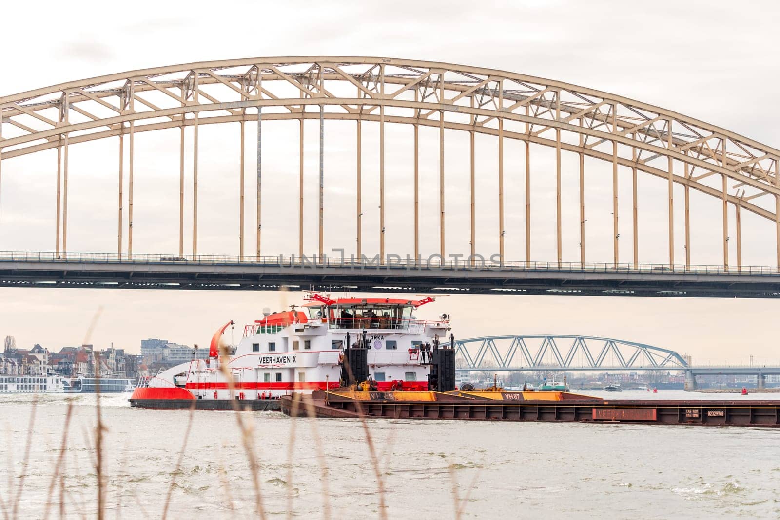 NIJMEGEN, NETHERLANDS - MARCH 9, 2024: Enormous dutch barge navigating the Waal river with a load of black sand