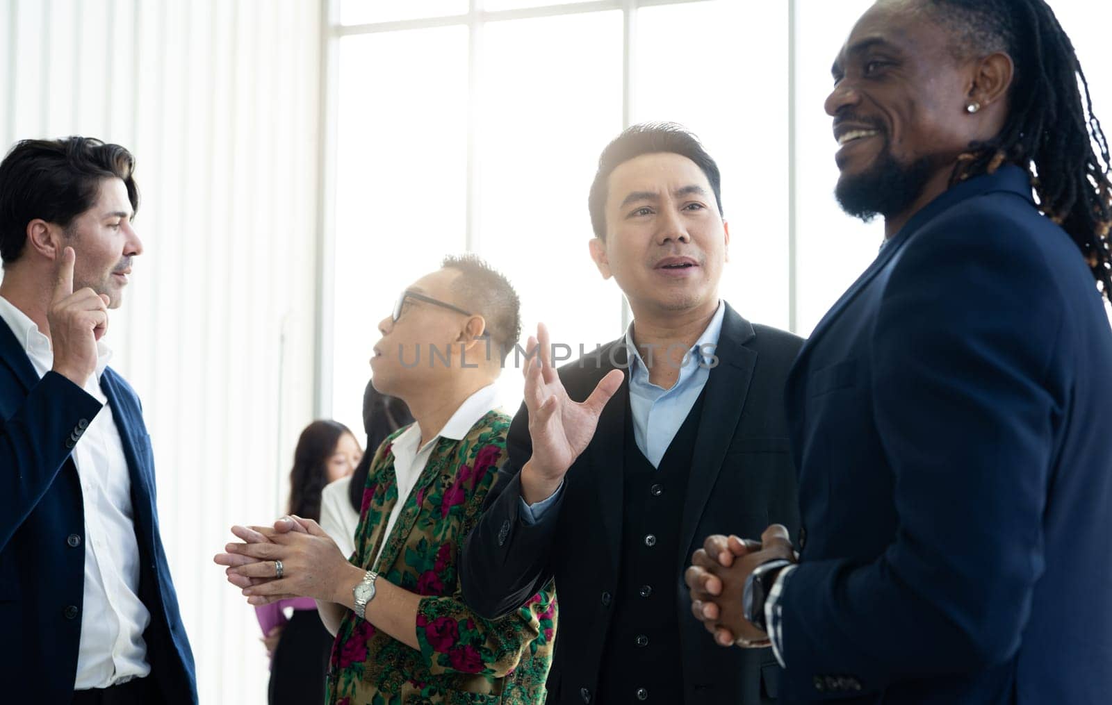 A group of men are standing in a room, one of them is wearing a suit and the others are dressed in business attire. They are all smiling, indicating a friendly. Business concept.