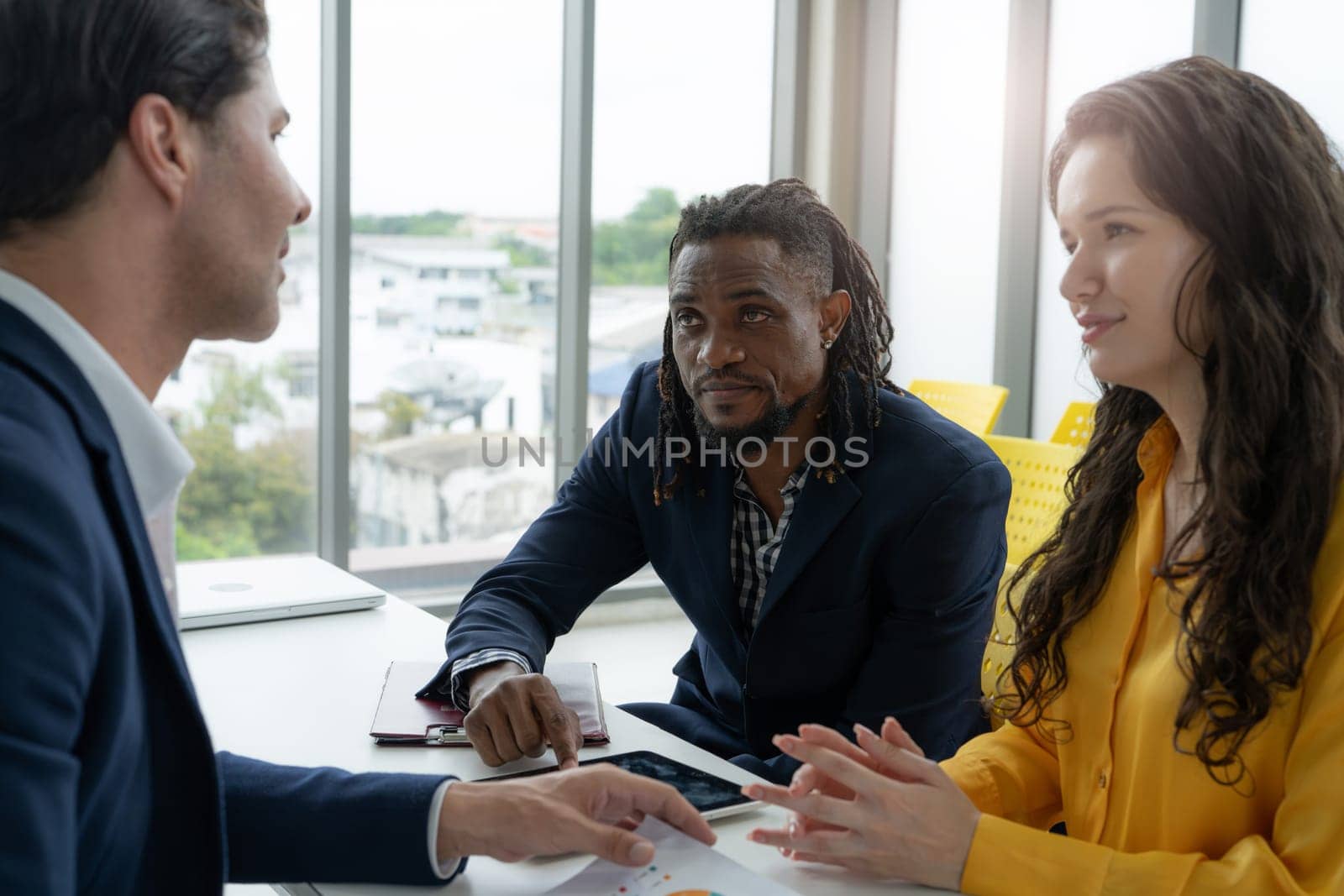 A man and a woman are sitting at a table with a man in a suit