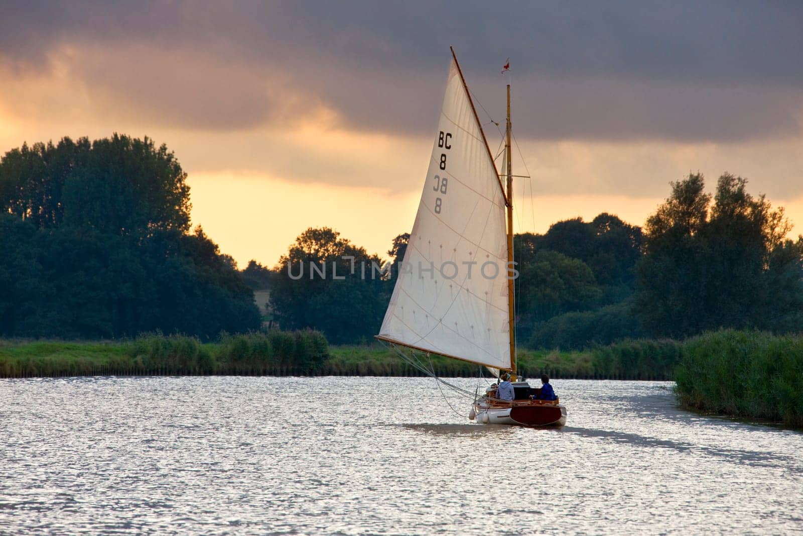 Norfolk. England. 09.13.08. Yacht on the Norfolk Broads at dusk. The Norfolk Broads are made up of rivers and partly man made lakes in the fens of Norfolk in southeast England. The lakes are the result of peat harvesting, where the working have become flooded. The area is now a popular vacation destination and the wetland areas are important wildlife reserves.