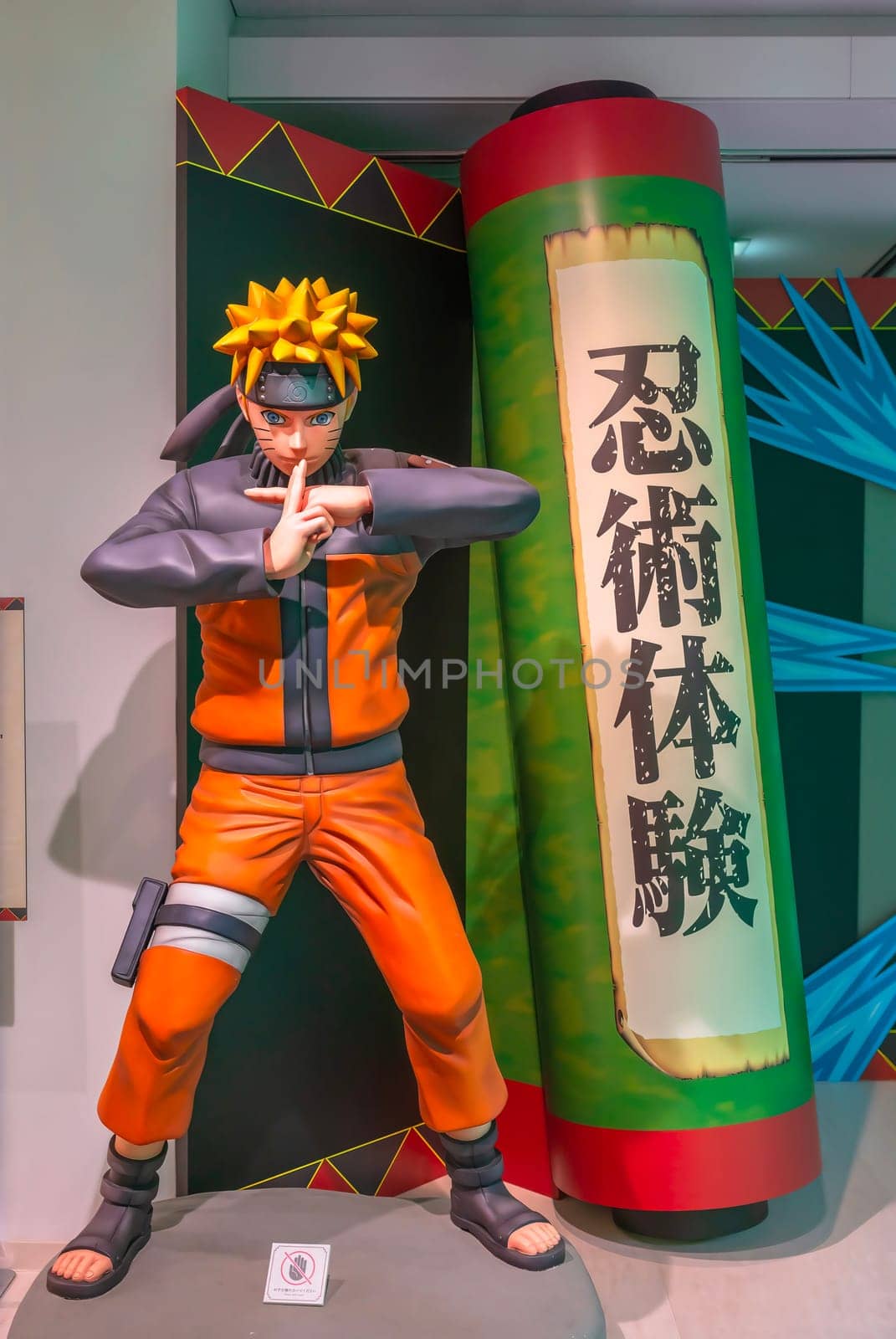 ikebukuro, japan - jan 16 2024: Life sized manga figurine of the ninja Naruto making a jutsu attack aside a scroll written 'Experience Ninja Martial Art' at the free exhibition of Anime Tokyo Station.
