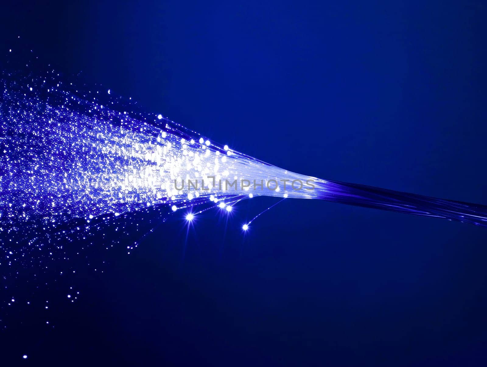 Macro image of a fiber optic cable emitting blue light particles, symbolizing high-speed Internet access.Tech industry advertisements, internet service promotions