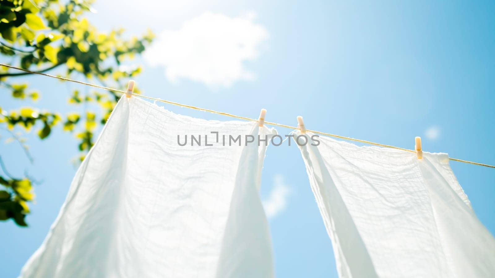 White laundry hangs on a line against a clear blue sky, reminiscent of freshness and cleanliness.