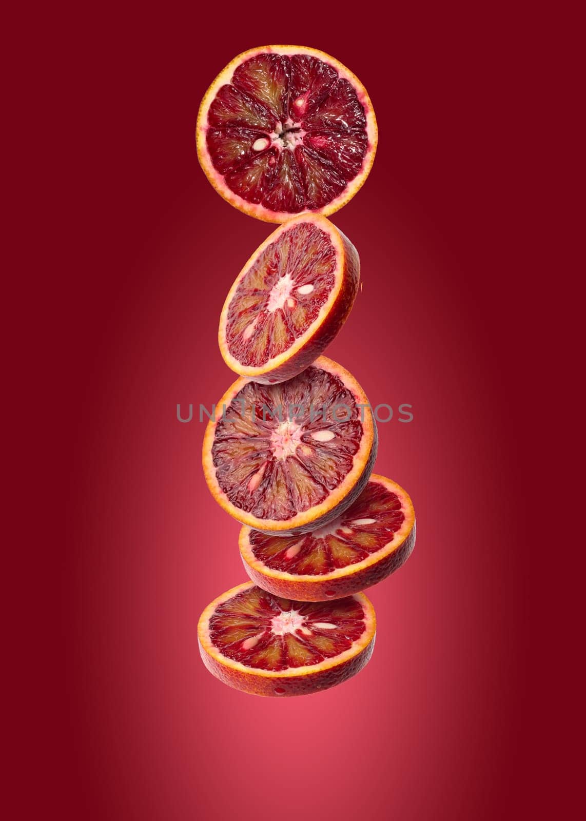 Round pieces of blood orange levitate on a red background, juicy fruit