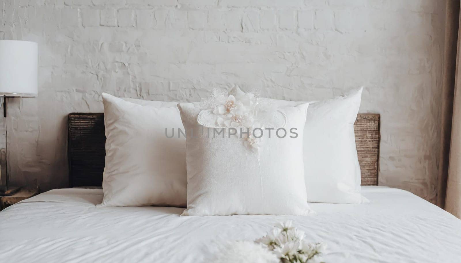 Clean Bedding sheets and pillow on natural wall room background. White bedding and pillow in hotel room. White pillows on empty bed.