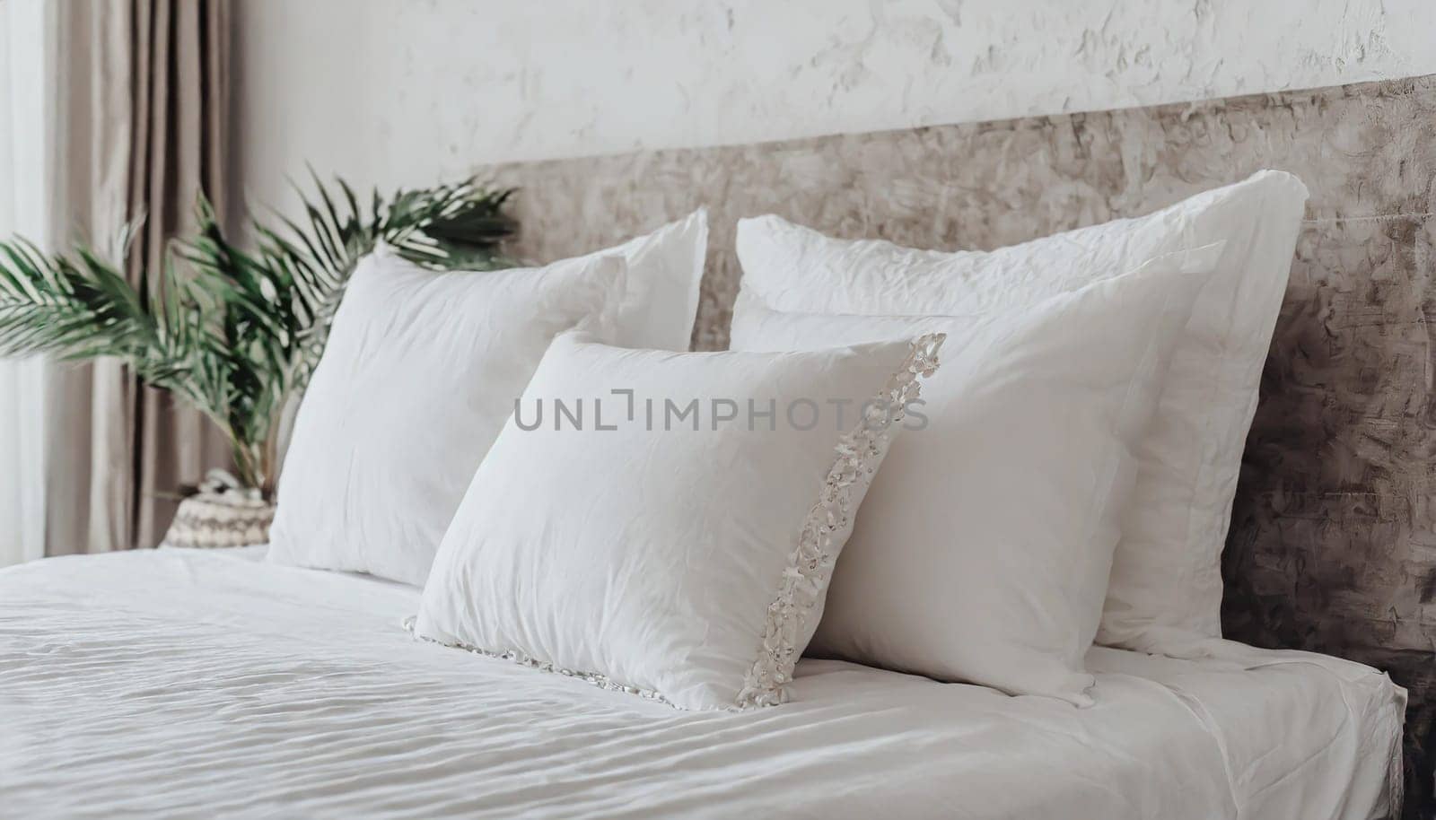 Clean Bedding sheets and pillow on natural wall room background. White bedding and pillow in hotel room. White pillows on empty bed.