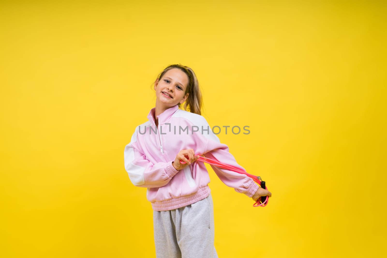 Beautiful sportsgirl with skipping rope isolated on a yellow studio