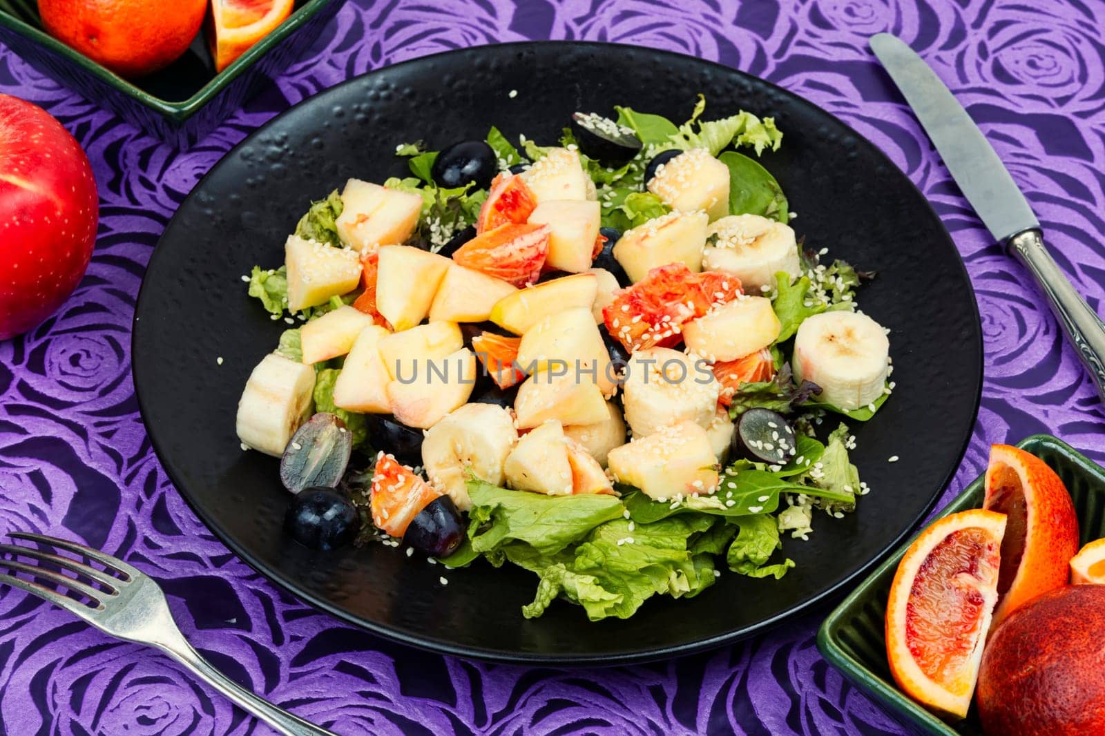 Fruit salad of red orange, apple, banana and lettuce. Healthy eating. Veggie vegan or vegetarian food.
