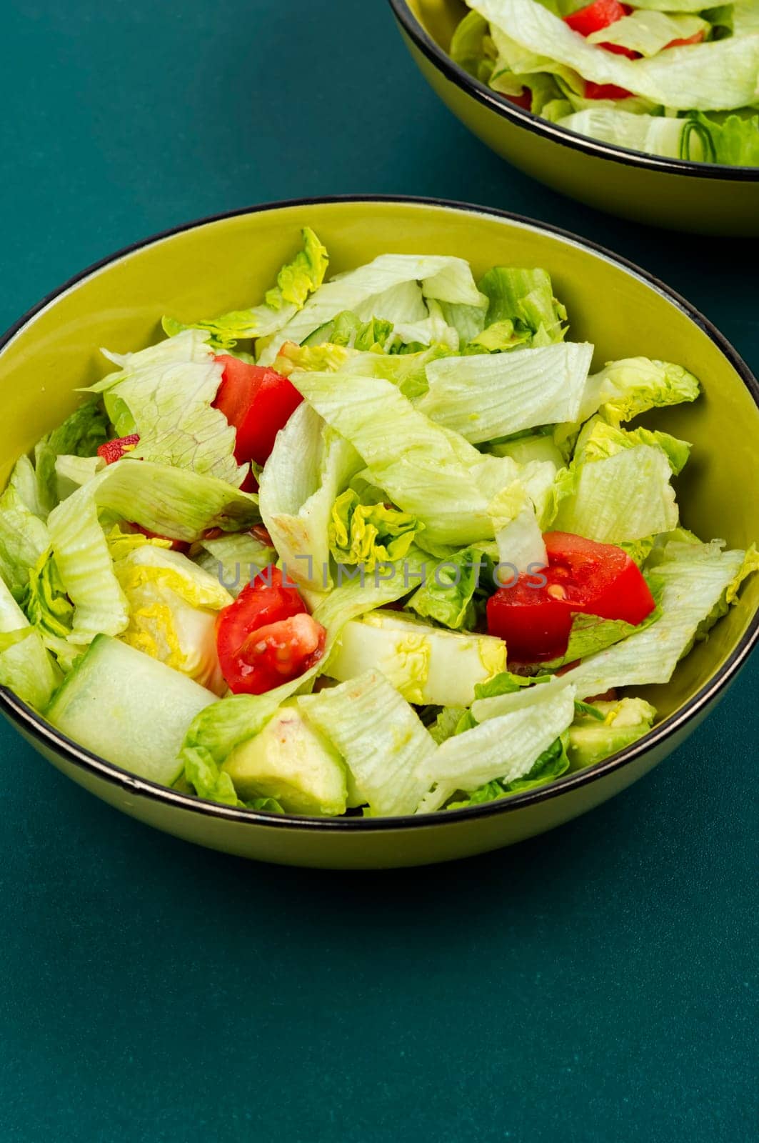 Healthy salad bowl with different lettuce, avocado, cucumber and tomato.