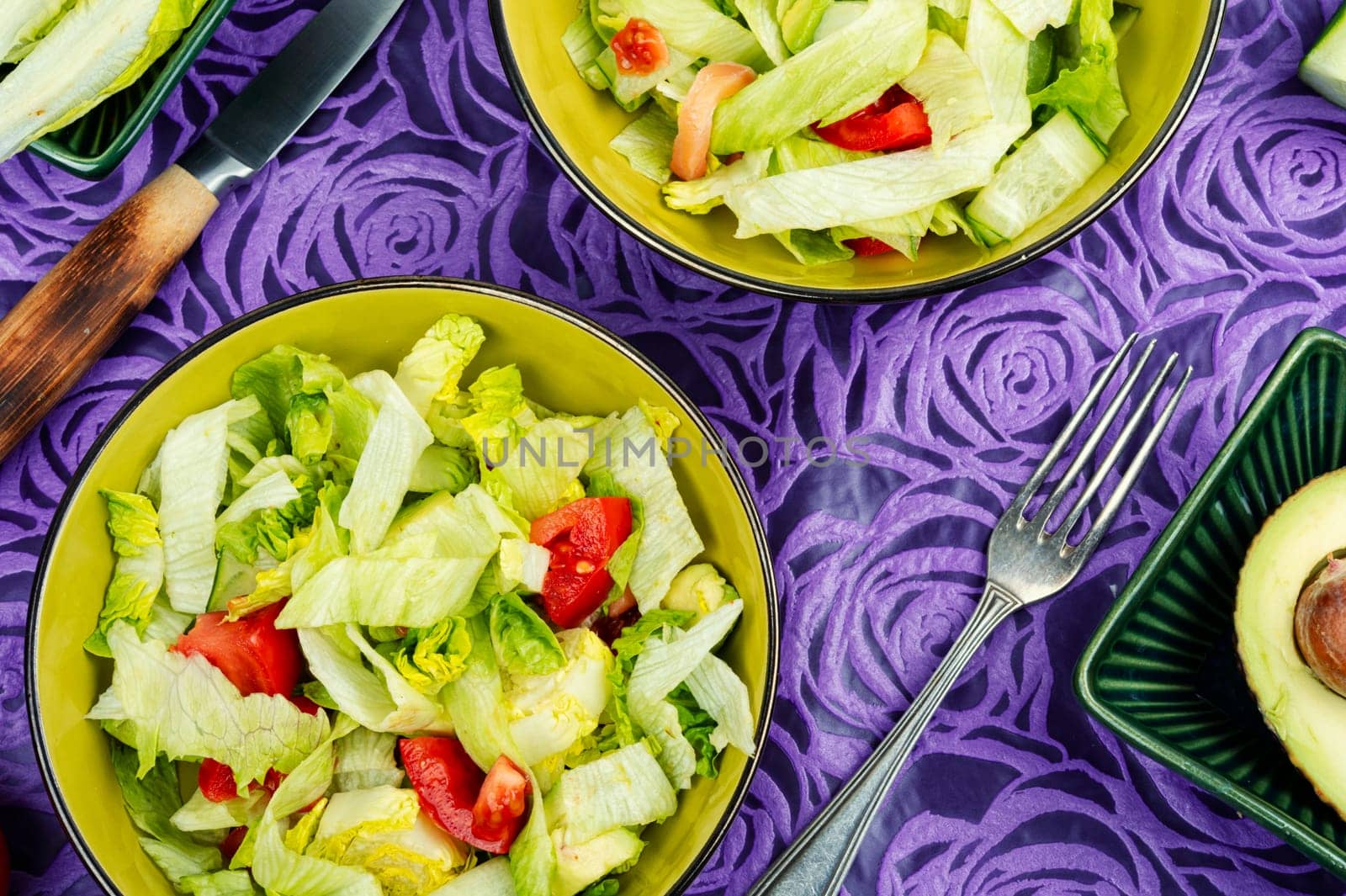 Healthy salad bowl with different lettuce, avocado, cucumber and tomato.