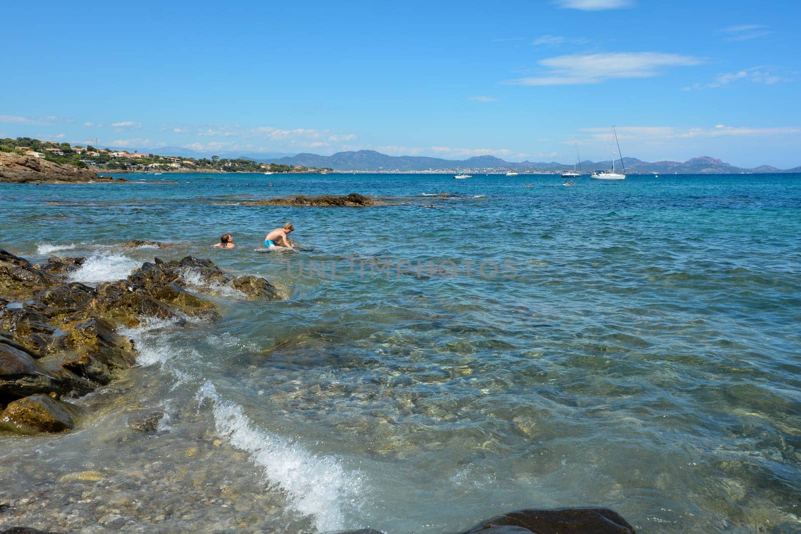 Two children play in the water on a rocky coast on the Côte d’Azur in France