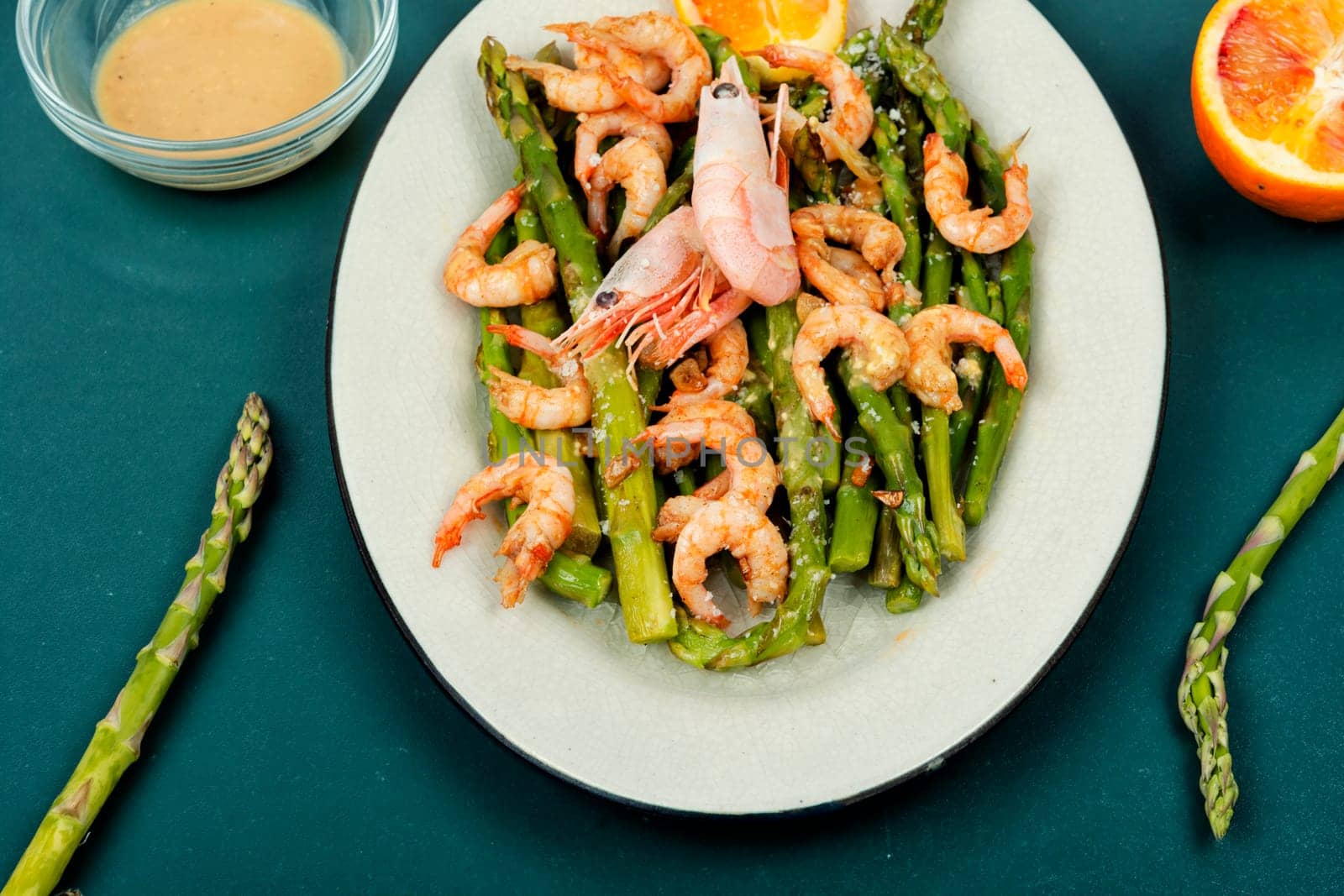Roast asparagus with fried prawns on rustic wooden table. Top view, copy space.