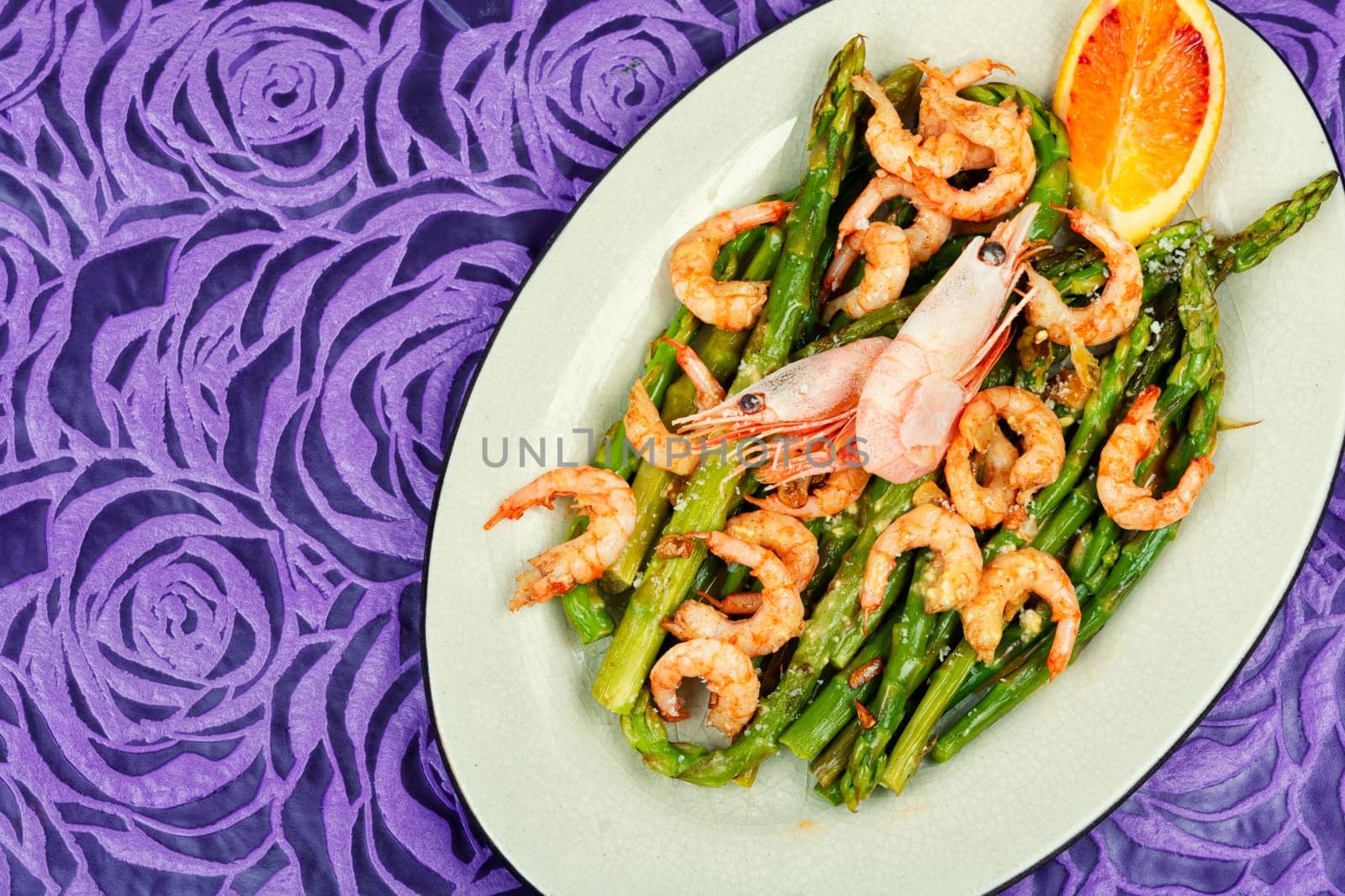Roast asparagus with fried prawns on rustic wooden table. Top view, copy space.