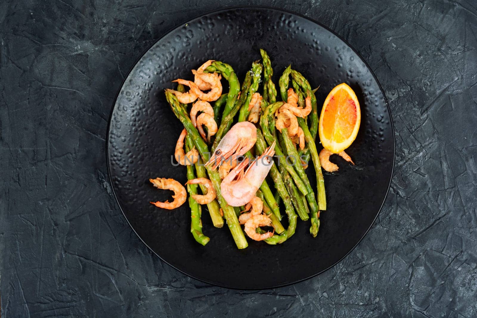 Roast asparagus with fried prawns on rustic wooden table. Top view, copy space.