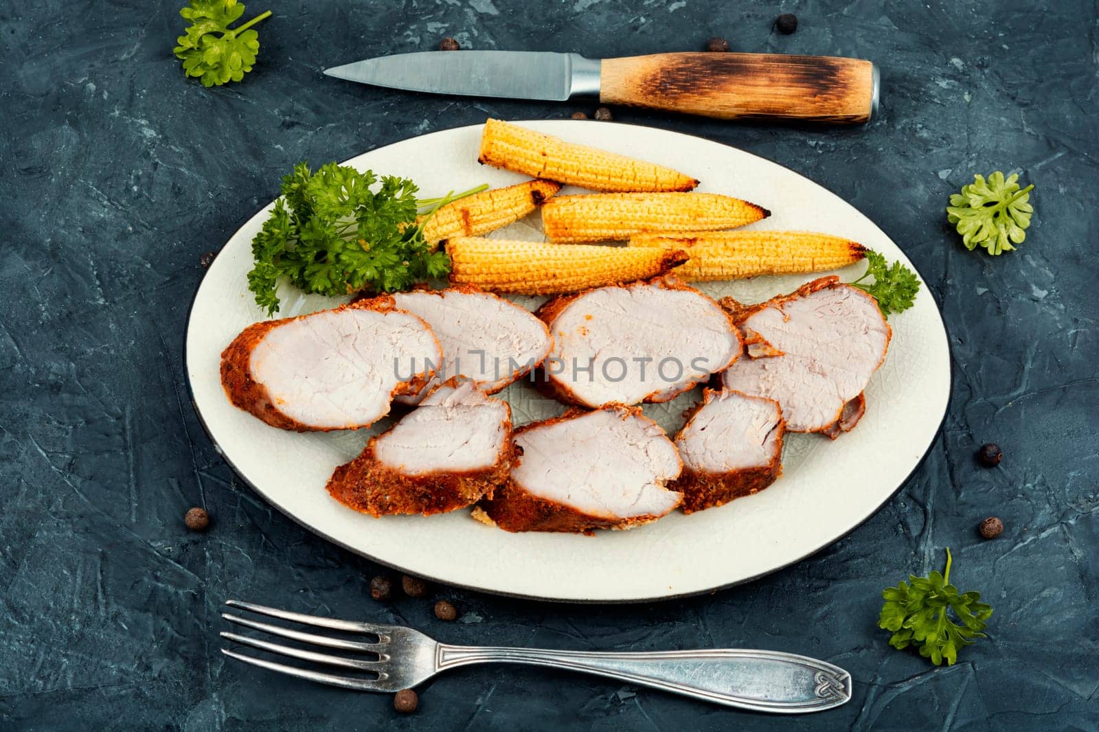 Sliced pork tenderloin grilled with corn. Baked meat