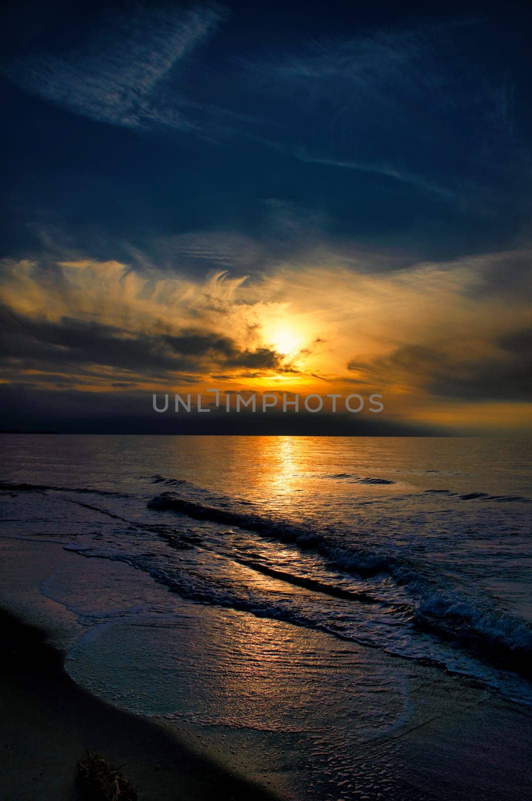 Sunset, illuminated sea. Sandy beach in the foreground. Light waves. Baltic Sea. Landscape on the coast