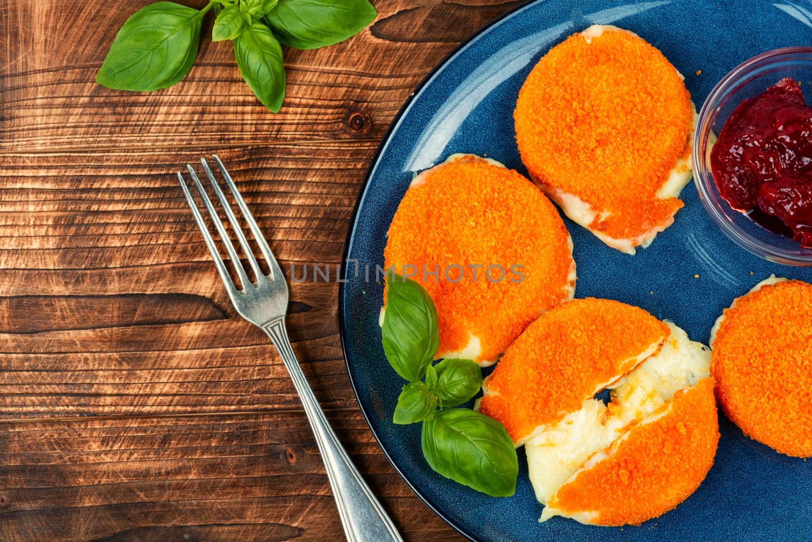 Fried camembert or brie cheese with berry jam and basil. Cheese baked in the oven.