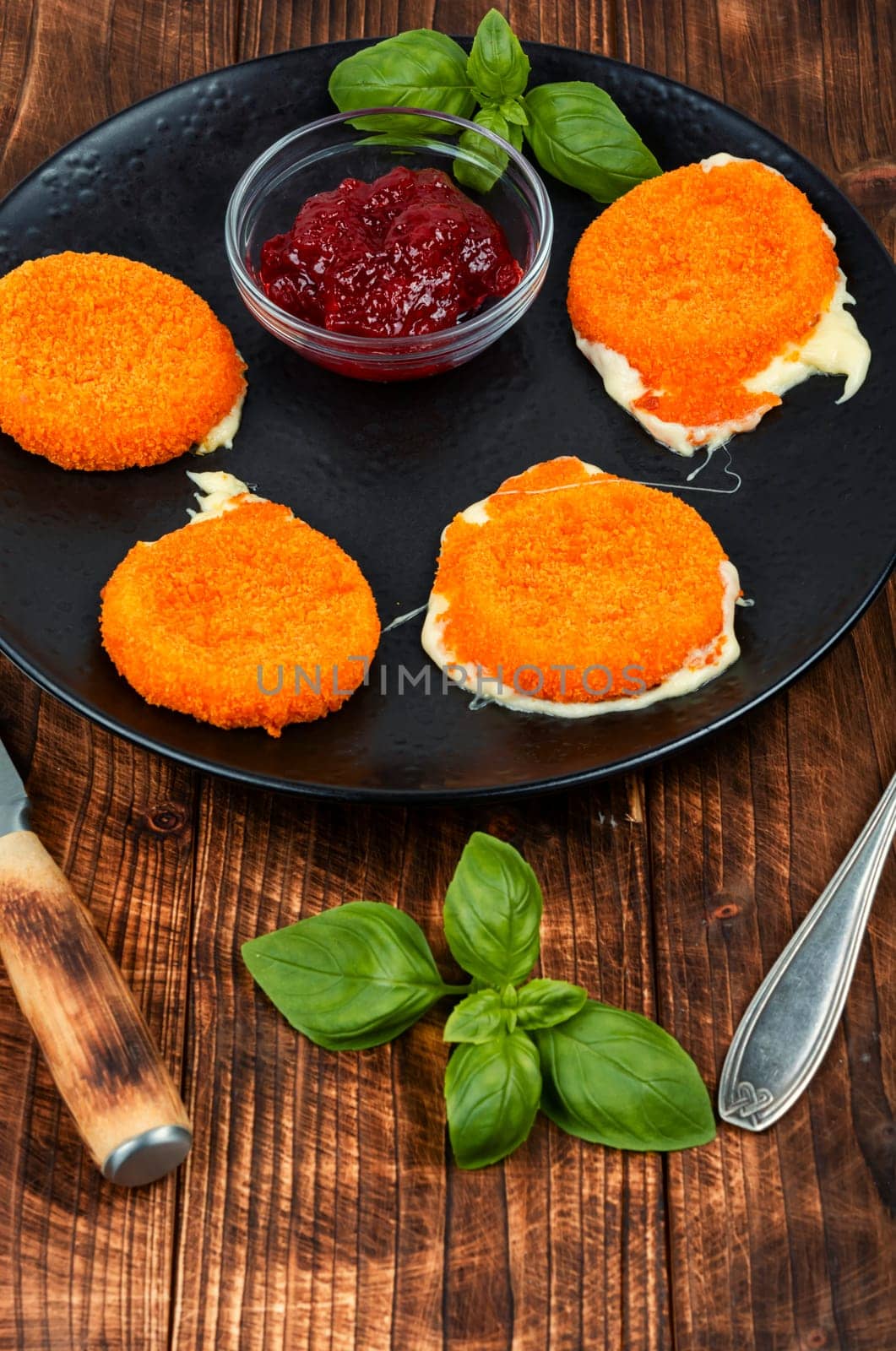 Fried camembert or brie cheese with berry jam and basil. Cheese baked in the oven.