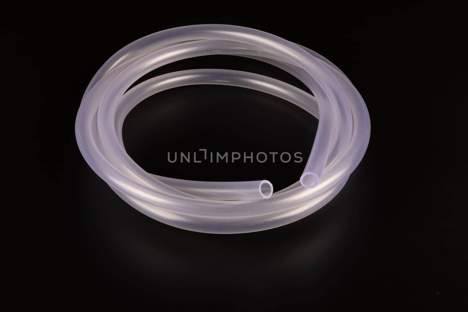 transparent plastic tube coil on black background.
