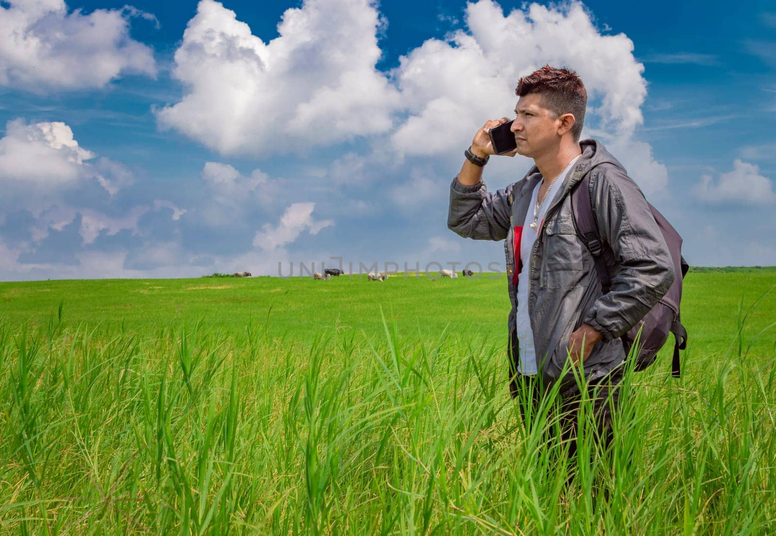 Man calling by cell phone, young man in the field calling by cell phone, young backpacker with cell phone in the field and copy space
