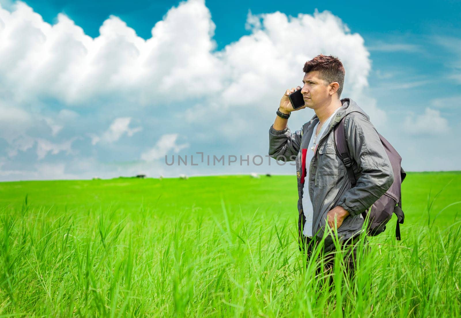 Man calling by cell phone, young man in the field calling by cell phone, young backpacker with cell phone in the field and copy space