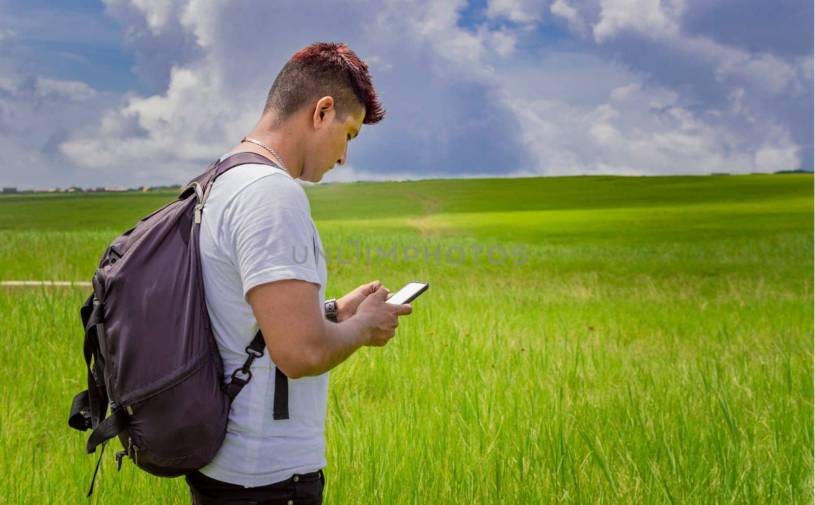 Man calling by cell phone, young man in the field calling by cell phone, young backpacker with cell phone in the field and copy space