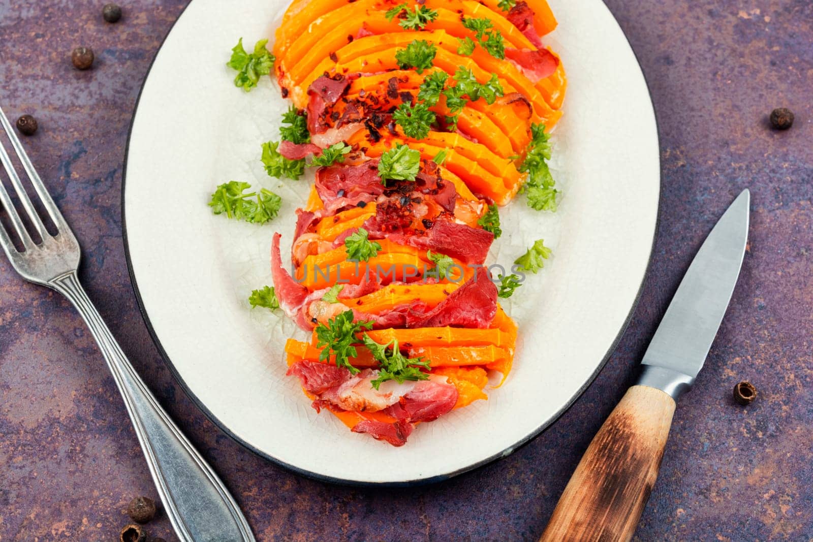 Plate with roasted pumpkin with bacon. Baked butternut squash with bacon. Copy space.