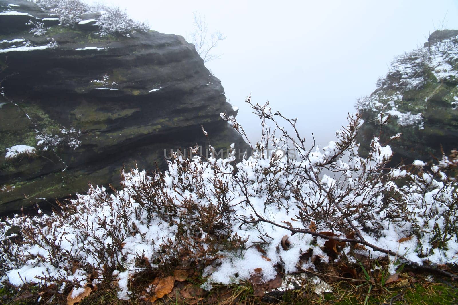 On the large Zschirnstein in fog. Rock covered with snow. Viewpoint during a hike. From the nature park in the Elbe Sandstone Mountains. Landscape in Germany