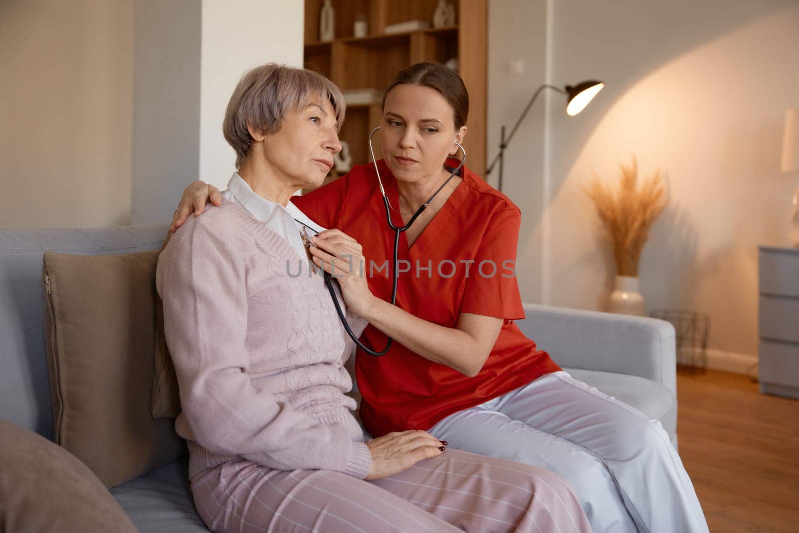 Woman doctor using stethoscope while examining senior woman at nursing home. Professional healthcare physical checkup for old people on retirement