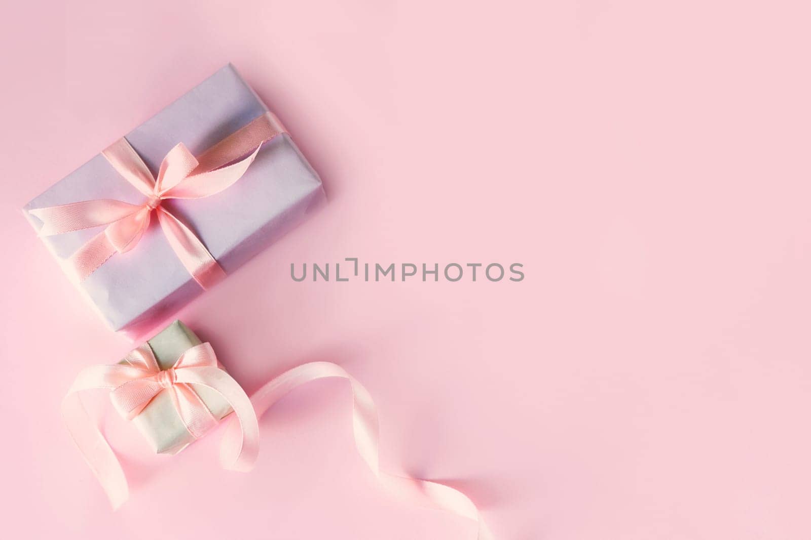 Greeting card with two gift boxes with pink ribbon bows. Top view with space for your greetings on pink background. Spring holiday, present. Valentine, mother, father day.