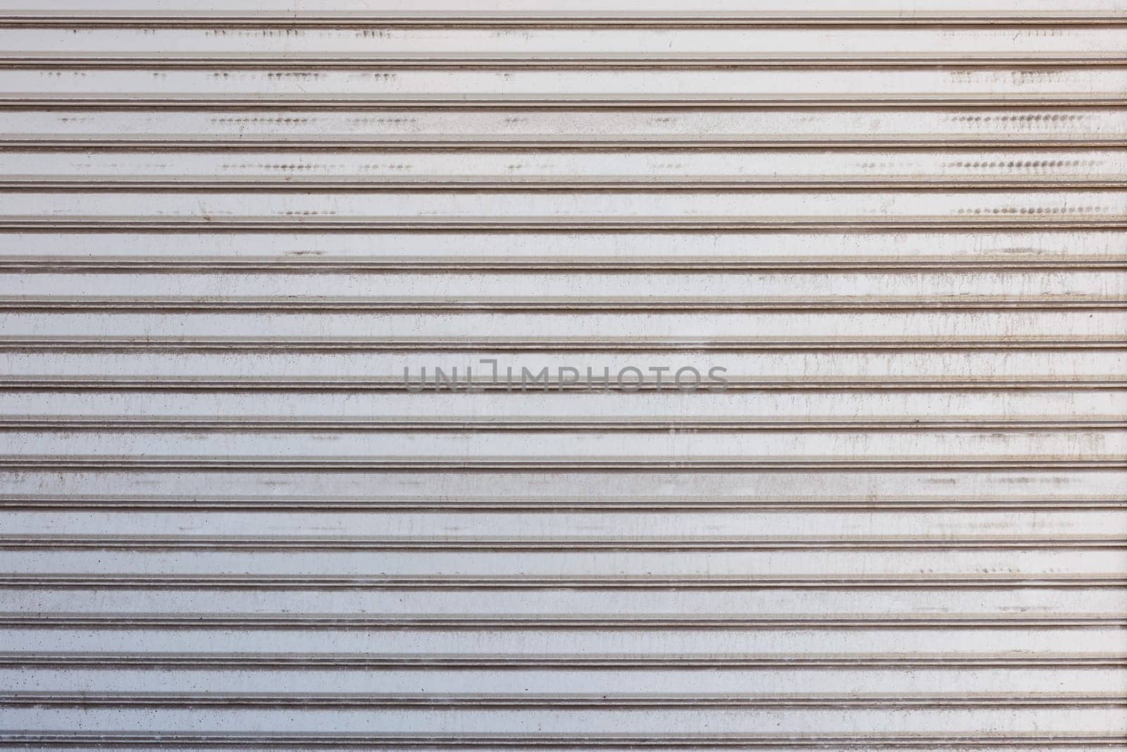 Closeup of a weathered and dirty metal shutter with horizontal folding lines