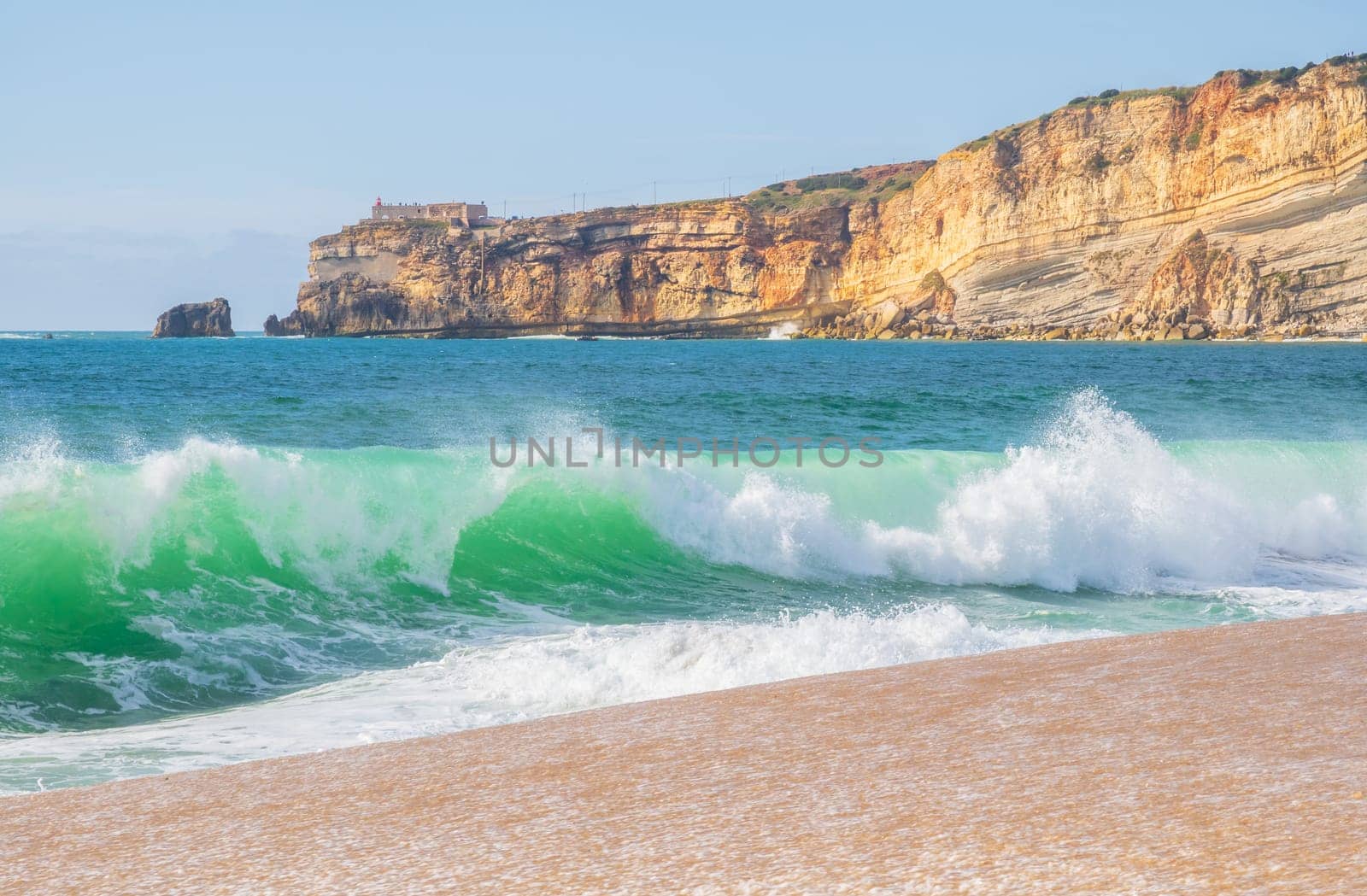 Wave and cliffs in Atlantic Ocean on the beach in Nazaré, Portugal.