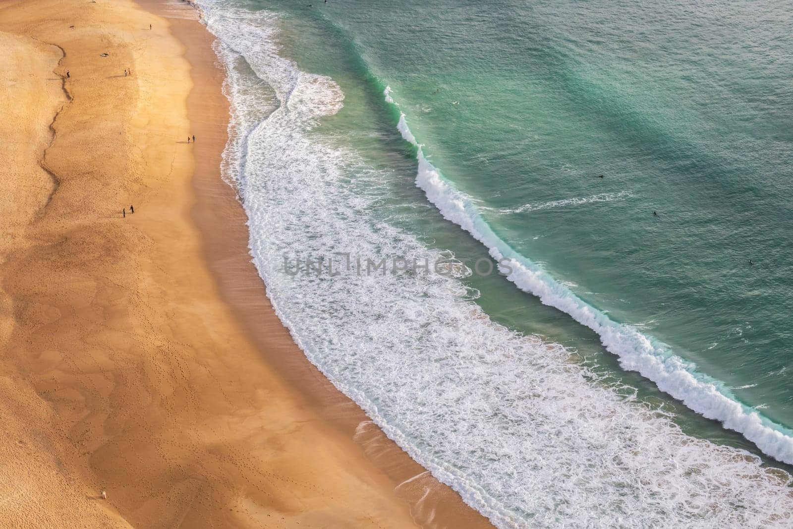 Aerial view of the sandy beach and the turquoise waves of the Atlantic ocean in Nazaré, Portugal
