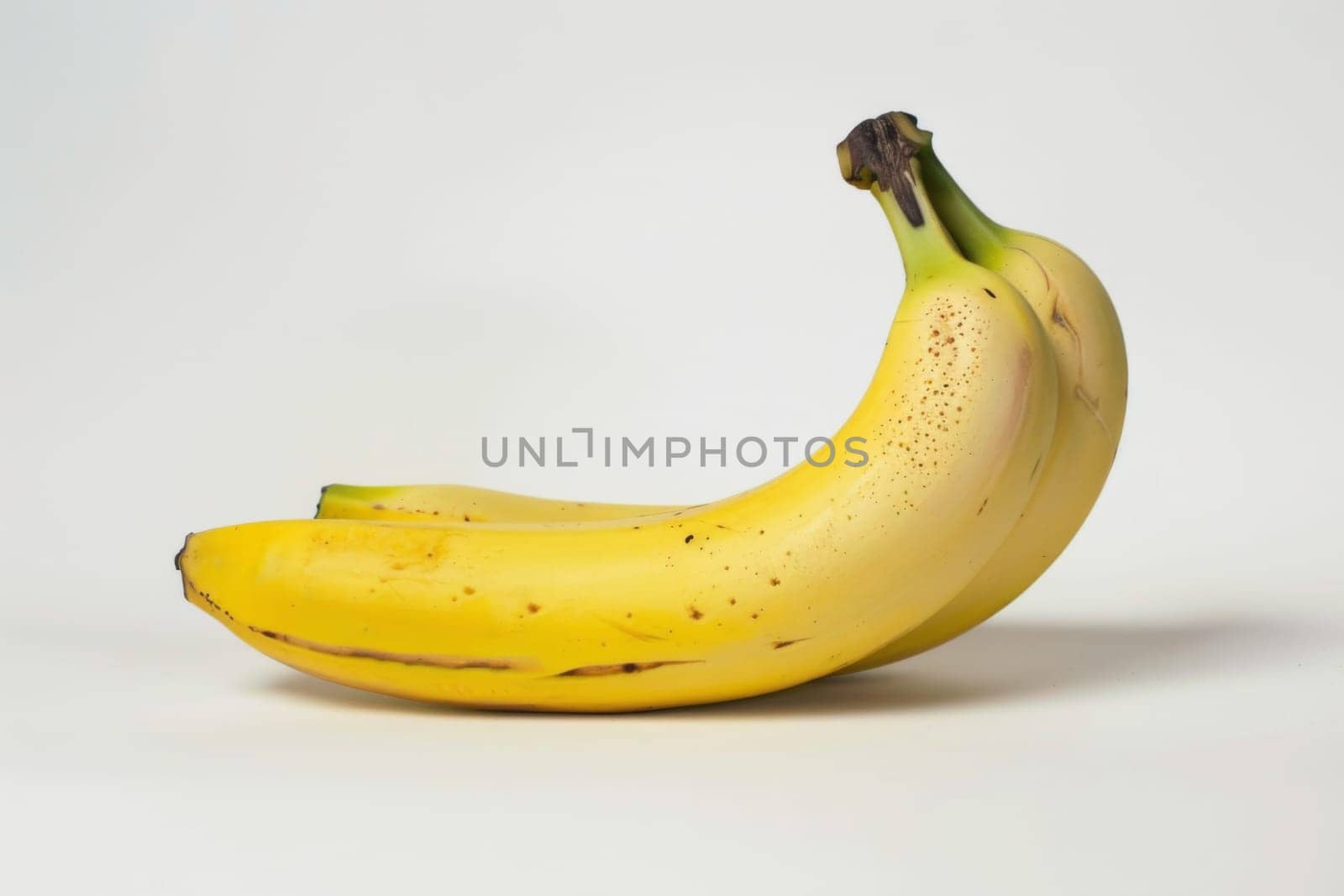 A ripe yellow banana is placed on top of a clean white table surface. The banana appears to be fresh and ready to eat, contrasting against the simple background.