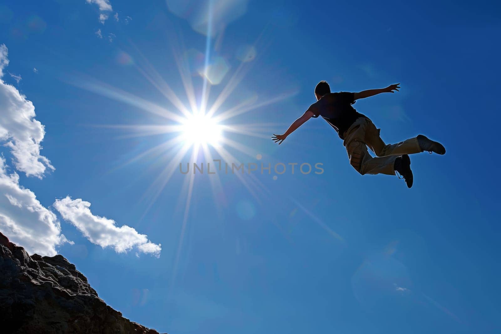 A man is seen jumping off a cliff, soaring through the air with an intense expression on his face. The backdrop is a rocky cliff with clear blue skies.