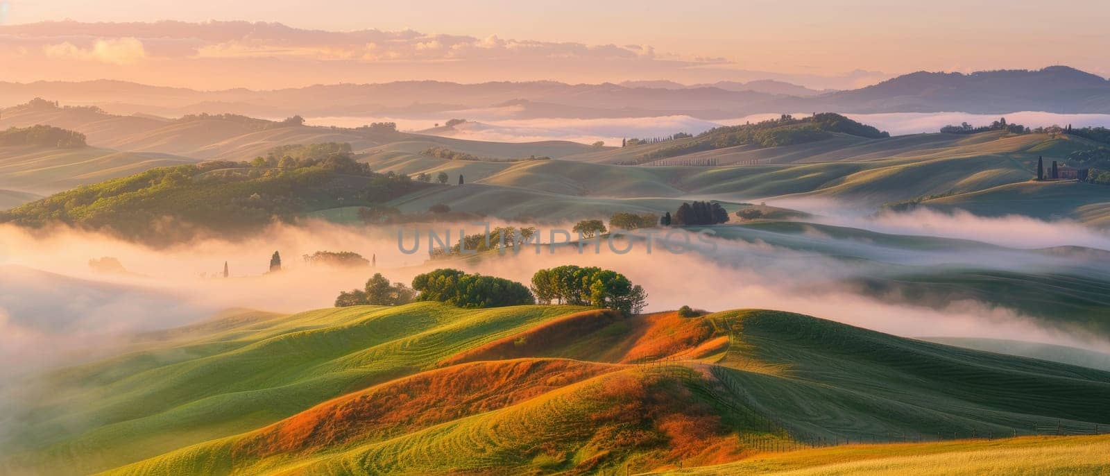 Undulating hills shrouded in mist under a pastel dawn sky create a tranquil and dreamy landscape