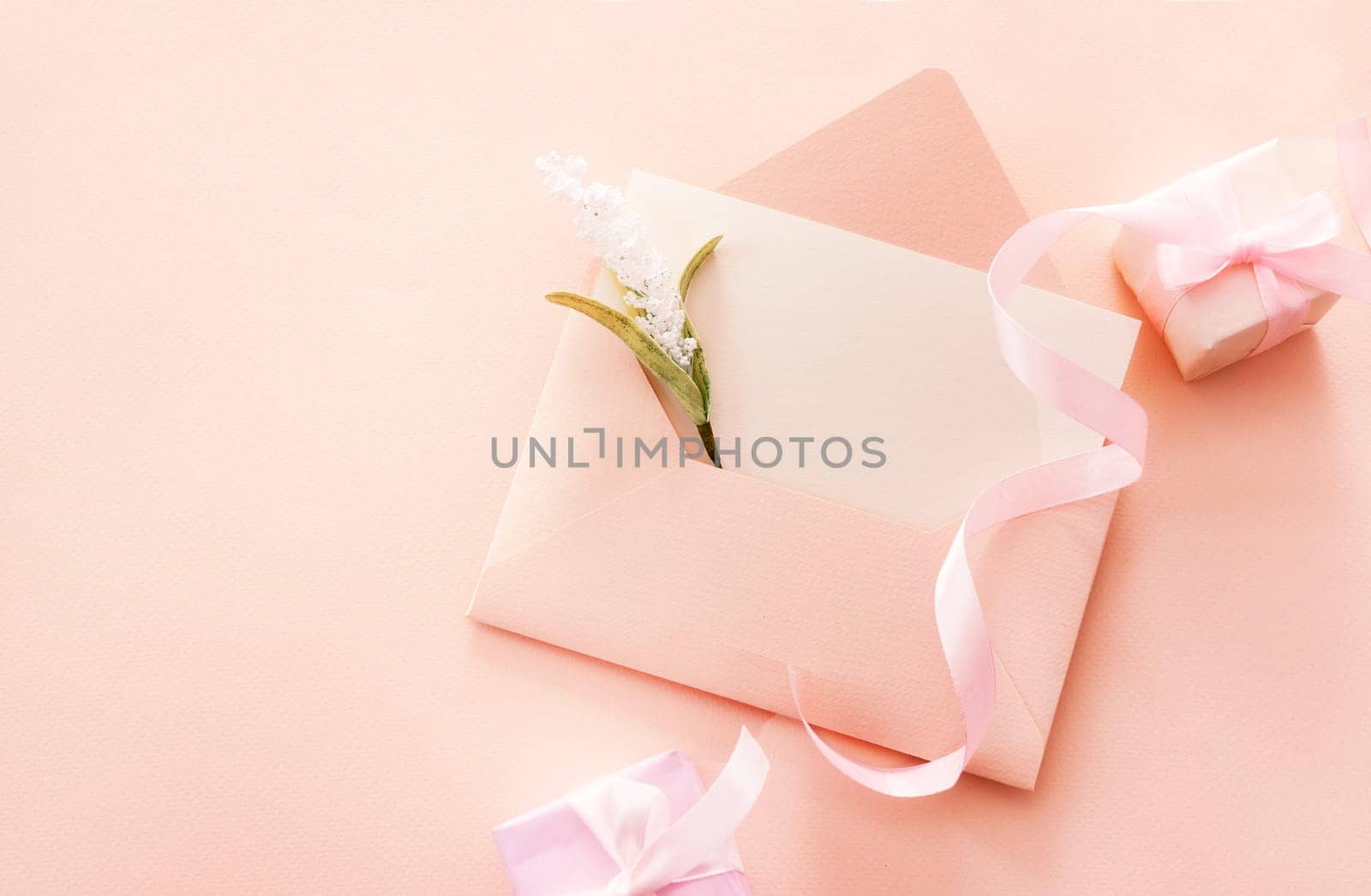 Greeting card with an open envelope and a flower and two gift boxes with pink ribbon with space. Spring vacation, gift, Valentines Day, Mothers Day, Fathers Day. Top view.