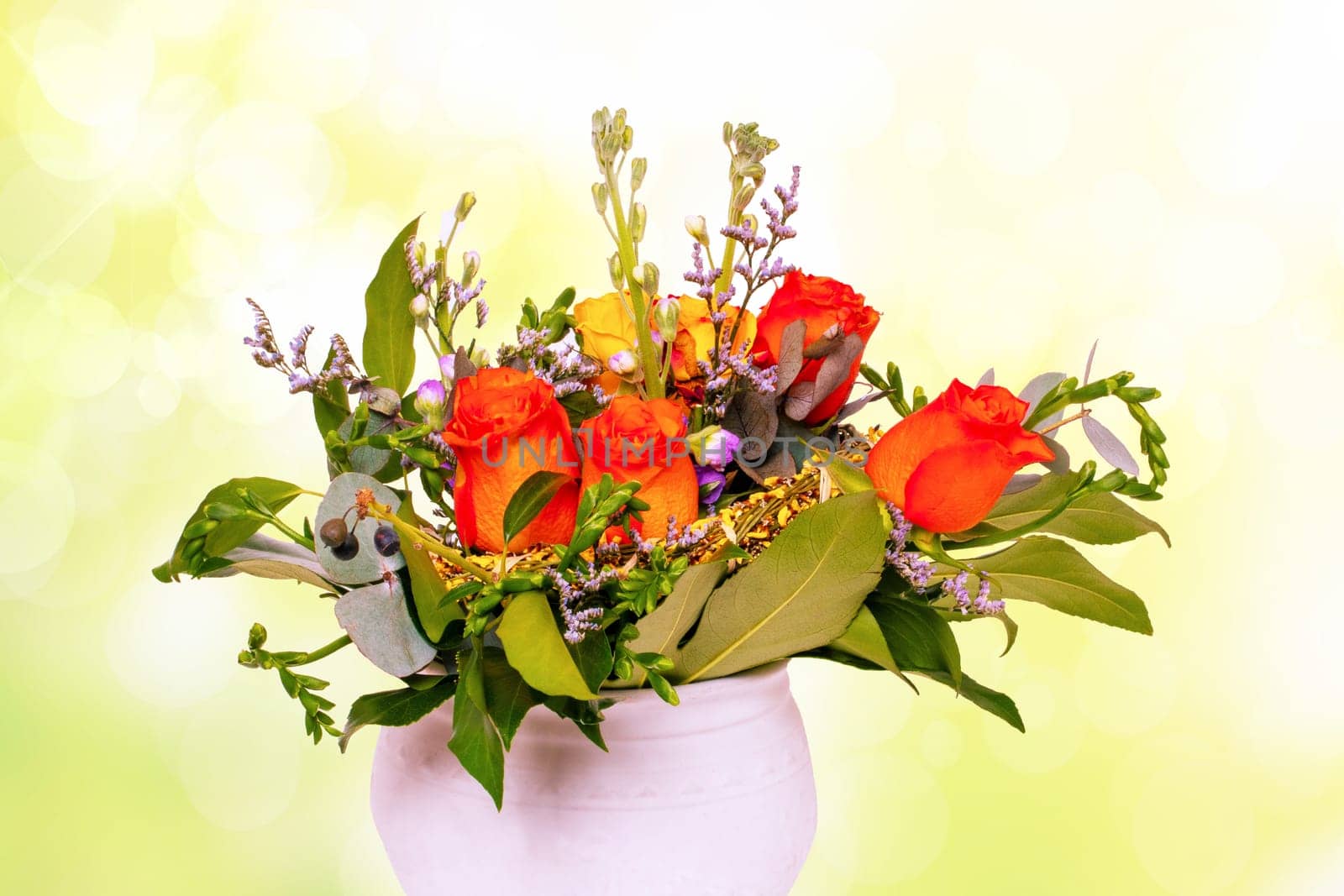 Closeup of a beautiful bouquet of bright red yellow roses in a vase over abstract yellow spring background texture for Valentine's Day, wedding or other holidays.