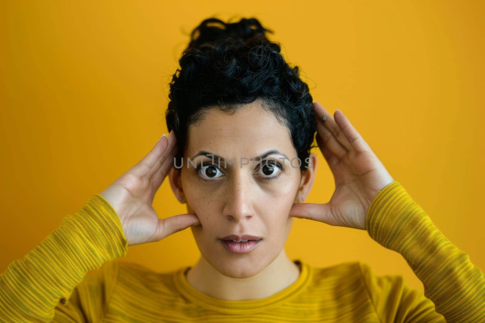A woman is shown holding her head with both hands in a gesture of distress or overwhelm. Her facial expression suggests inner turmoil or intense emotions, with eyes closed and furrowed brows.