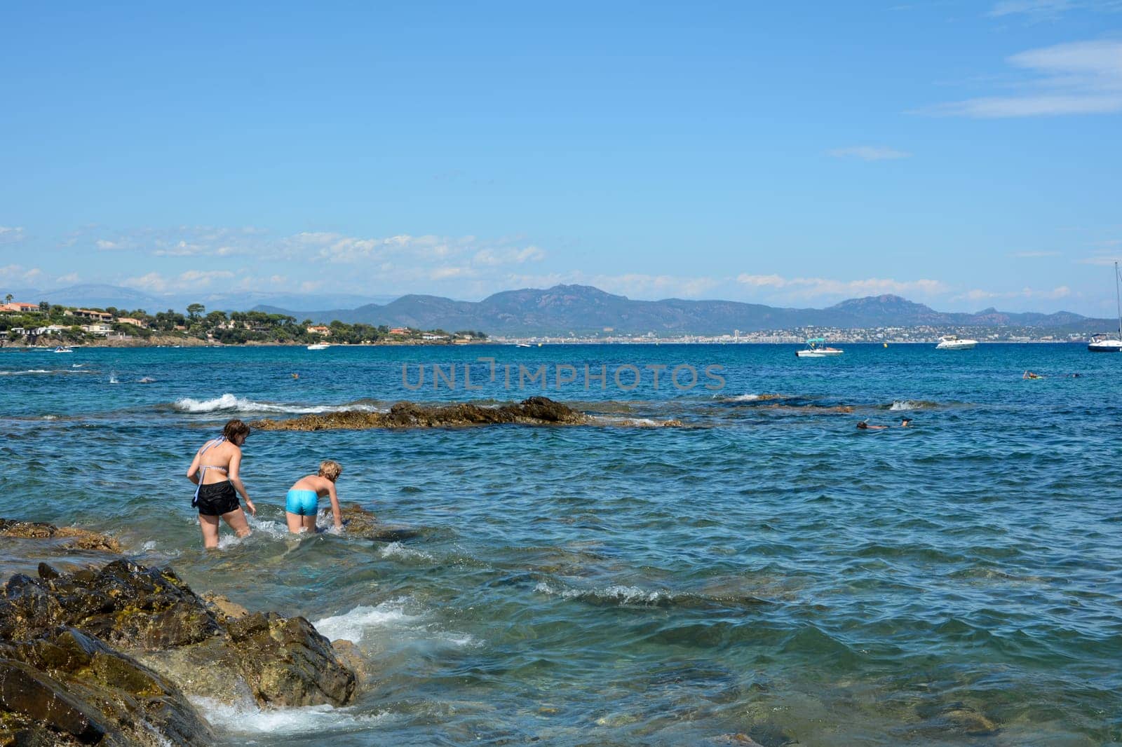 Two children play in the water on a rocky coast on the Côte d’Azur in France