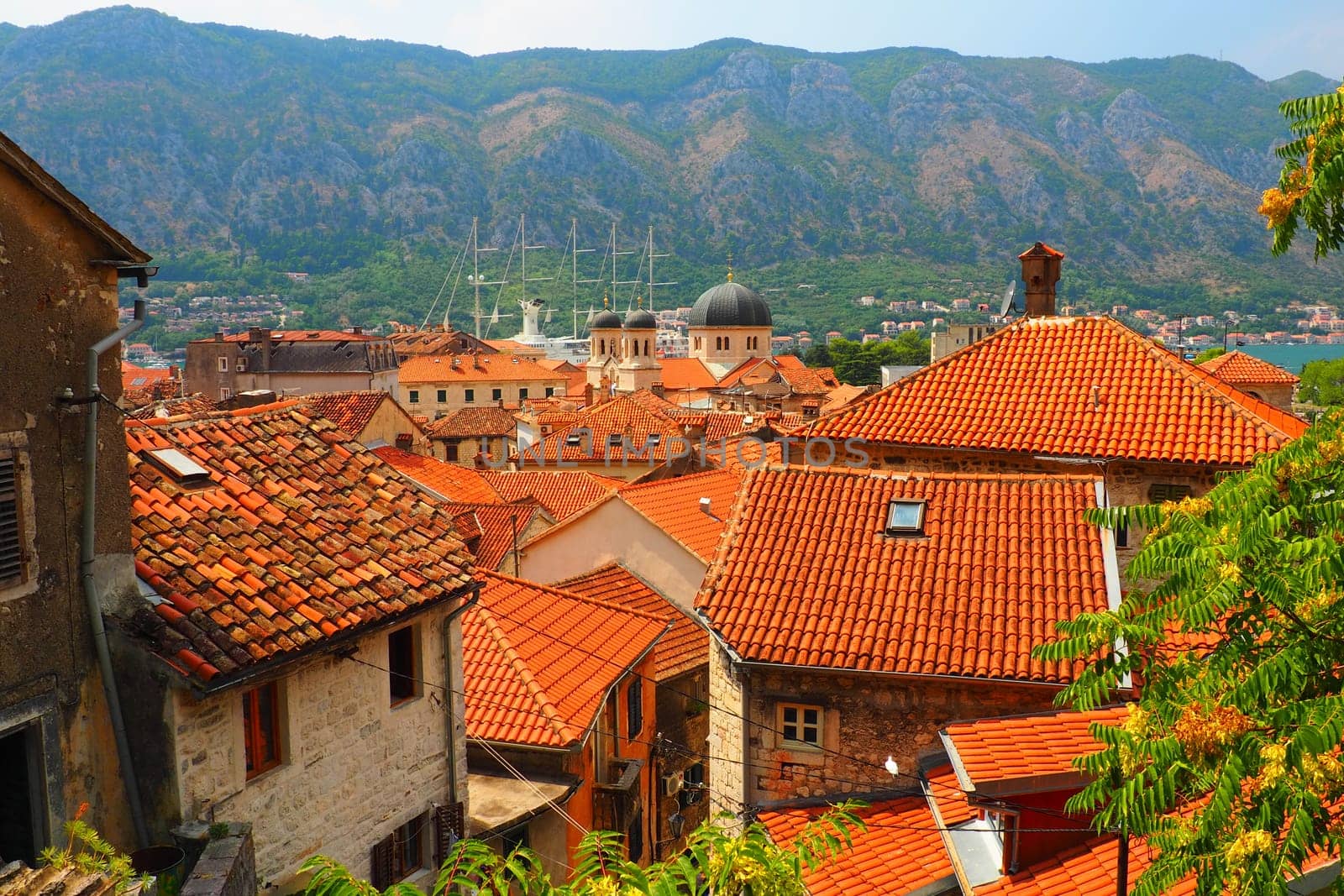 Kotor is a coastal city in Montenegro. Bay of Kotor. Red tiled roofs, mountain and chimneys of a tourist ship. Excursions and tourism. Cathedral of Saint Tryphon. Medieval old towns in the Adriatic.