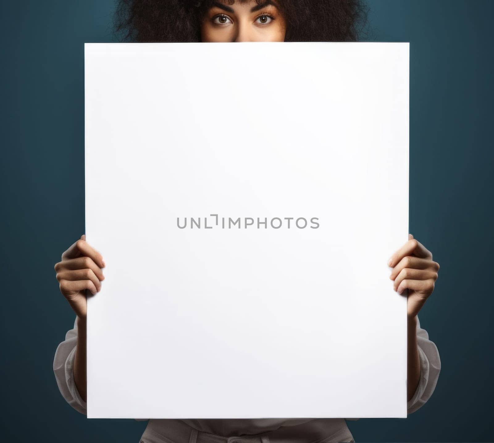 A woman holds a blank white sheet of paper in front of her face.