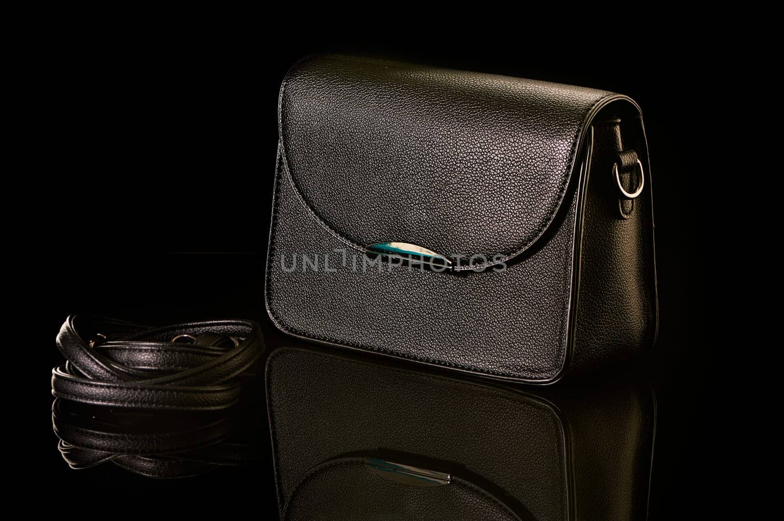A black handbag stands on black glass. High quality photo