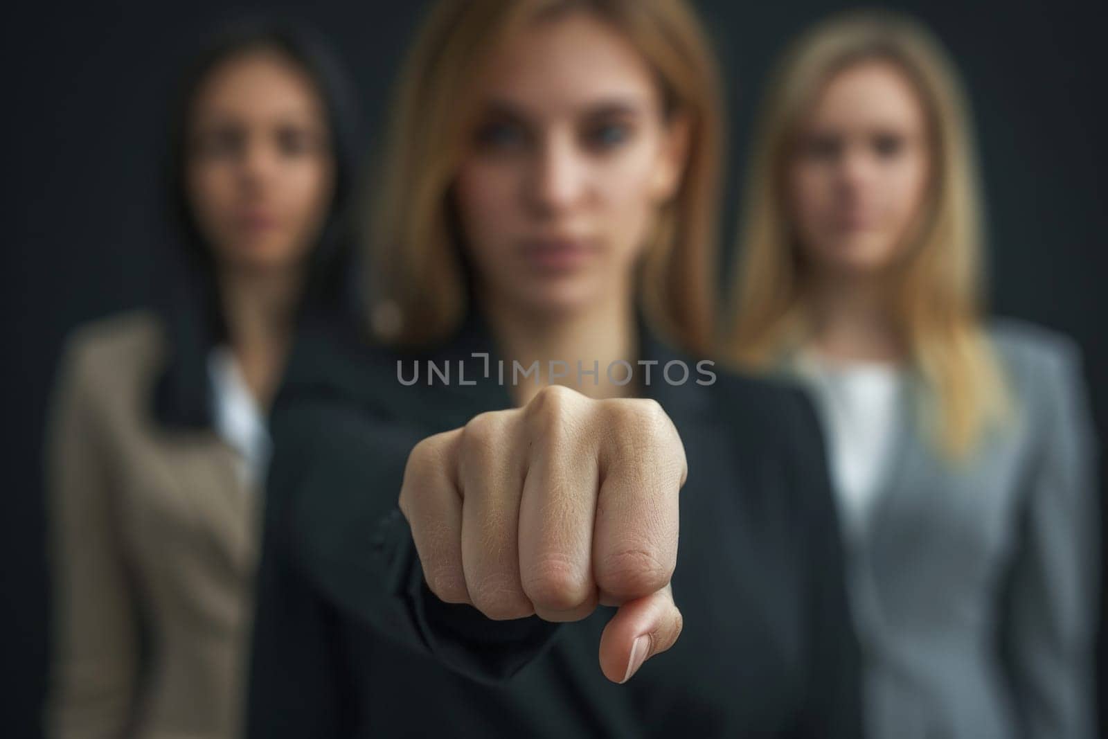 A focused woman with her team behind her points directly at the viewer, signaling recruitment.