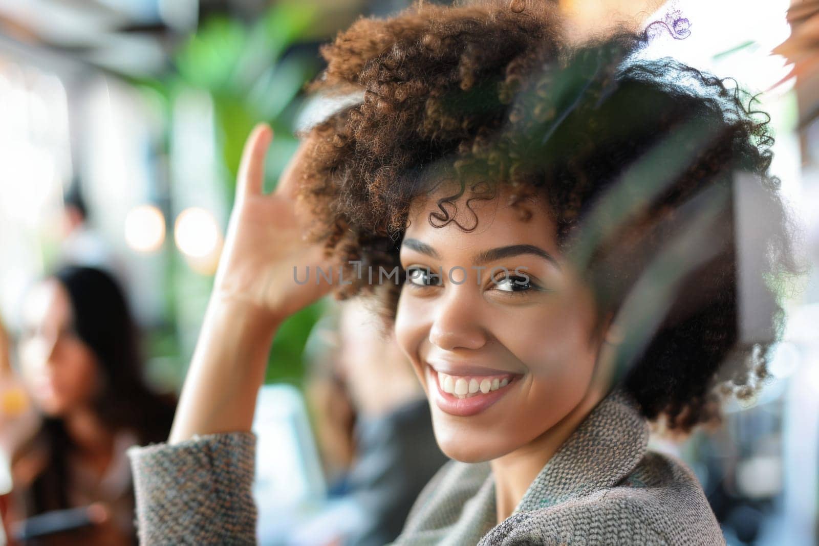 A woman with curly hair smiling directly at the camera, exuding joy and confidence in her expression as she poses for the photograph.