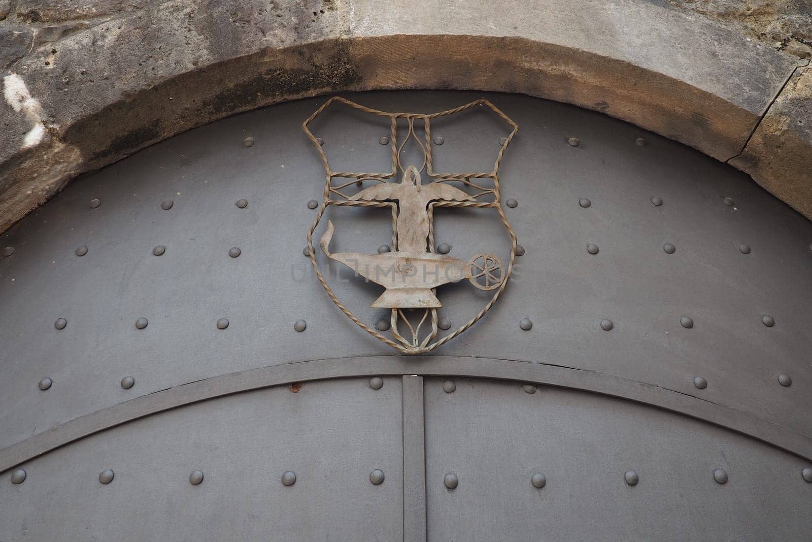 Fortress metal door with rivets. Old medieval castle in Kotor, Montenegro. Entry iron door with pattern. Medieval style with rivets of steel. Forged figure of a man, a fire and a boiling vessel.