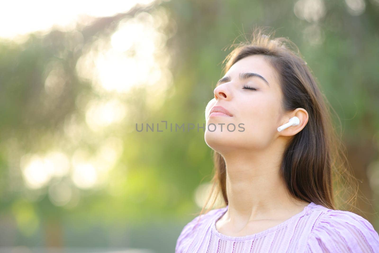 Woman breathing and meditating with earphone in a park